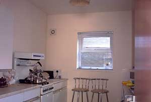 The kitchen, with cooker, microwave, cupboards, and seats